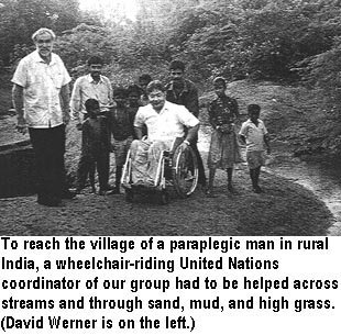 To reach the village of a paraplegic man in rural India, a wheelchair-riding United Nations coordinator of our group had to be helped across streams and through sand, mud, and high grass. (David Werner is on the left.)